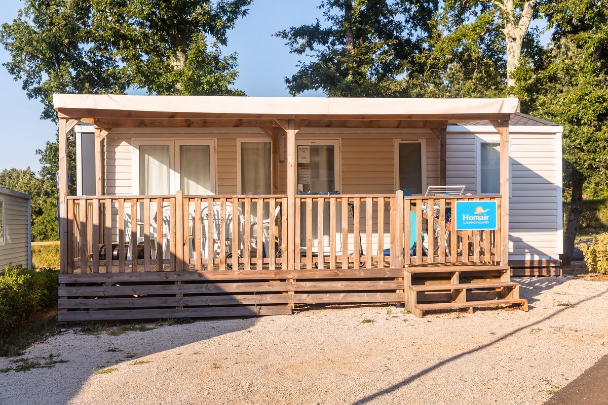 Stacaravan met een crèmekleurige luifel over de volle breedte van het terras op Camping Park Umag, aan een grindpad