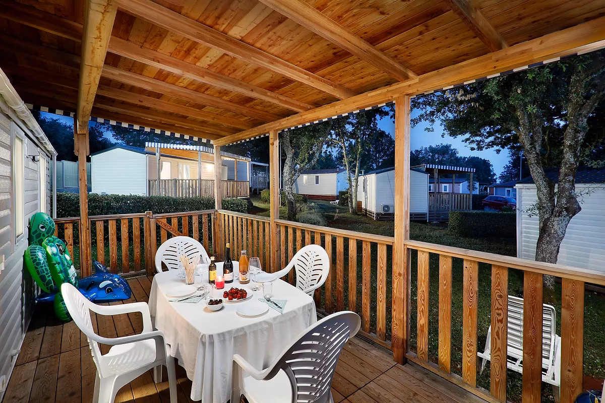 Gedekte tafel met wijn en dessert op een overdekt terras bij avondlicht, bij een stacaravan op Camping Park Umag