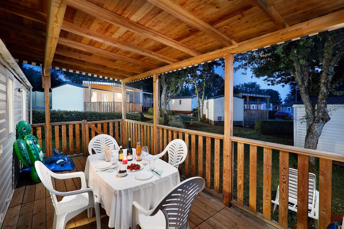 Gedekte tafel met wijn en dessert op een overdekt terras bij avondlicht, bij een stacaravan op Camping Park Umag