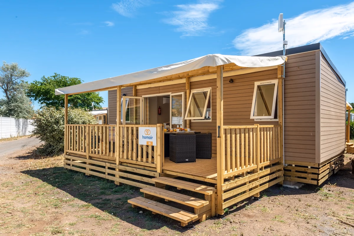 Stacaravan met houten gevel, klapramen en een luifel boven het terras op Camping Park Umag, met een trap naar de vlonder
