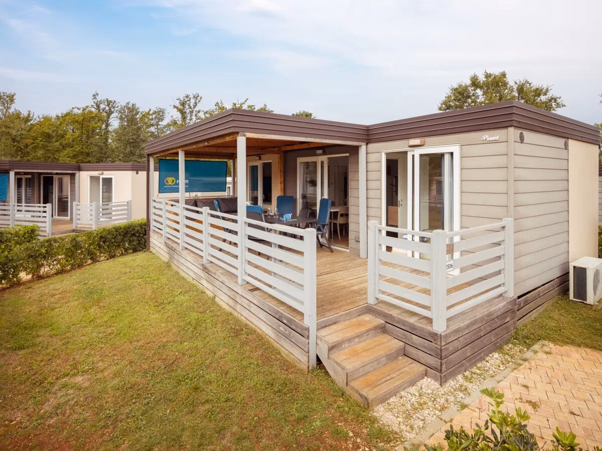 Stacaravan met een witte terrasafscheiding en houten vlonder in de Premium Zone van Camping Park Umag, met airco aan de zijkant