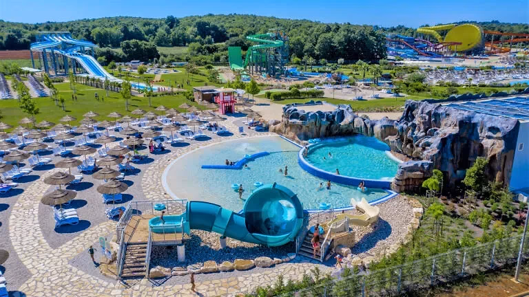 Luchtfoto van waterpark Aquacolors met glijbanen, een zwembad en rijen parasols