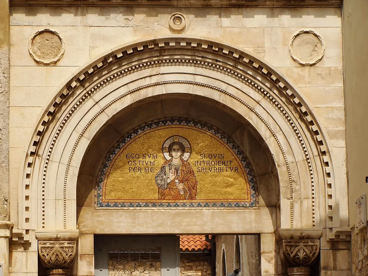 Een rond portaal met een goudkleurig mozaïek van een heilige boven de ingang van de Euphrasiusbasiliek in Poreč