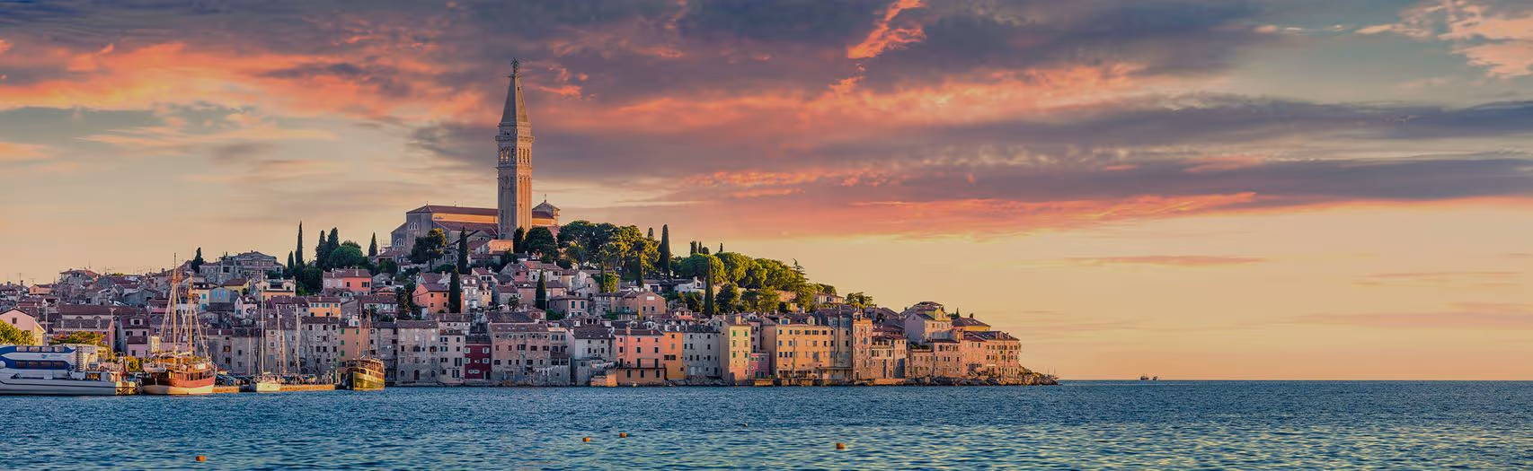 Het silhouet van Rovinj bij zonsondergang, met de klokkentoren hoog boven het schiereiland