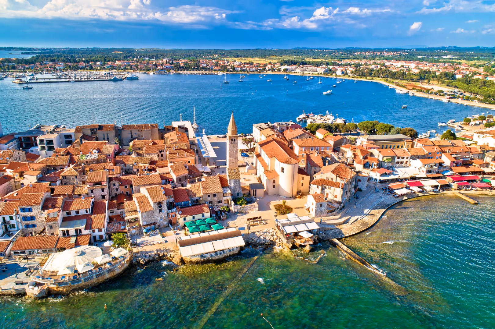 Luchtfoto van de oude stad van Umag op het schiereiland, met terrassen aan de waterkant en de jachthaven erachter